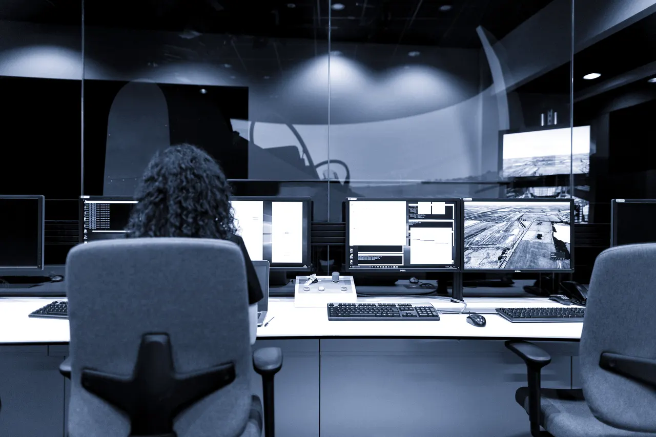 Sala de control industrial en penumbra con paneles de operación